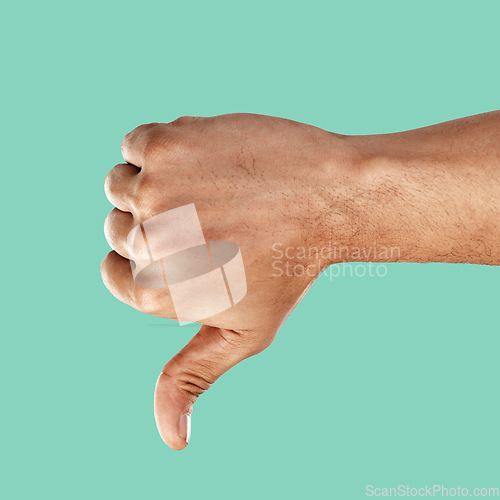 Image of Hand, thumbs down and negative emoji with a man in the studio on a green background for disagreement. Gesture, no and negativity with a male indoor to disagree, vote or voice his review and feedback