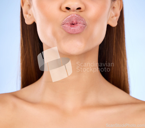 Image of Beauty, skincare and lips kiss with a model pout with lip gloss makeup in studio. Cosmetic, mouth and healthy natural glow of a woman with clear and smooth texture skin with isolated blue background