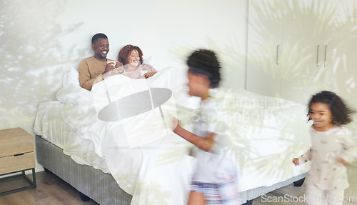 Image of Relax, family and children being playful in the bedroom while their parents lay in bed with a cup of coffee. Happy, love and young couple drinking a cappuccino while watching their kids run together.