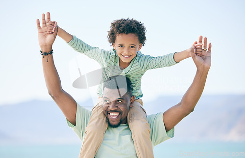Image of Black family, father and a son sitting on shoulders while outdoor in nature together during a beach vacation. Love, sky or kids with a parent carrying his male child while walking on the coast