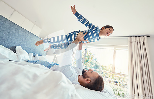 Image of Father, son and dad playing with his child on a bed holding him having fun in a bedroom feeling happy, carefree and excited. Parent, kid and dad bonding with young boy in a house together