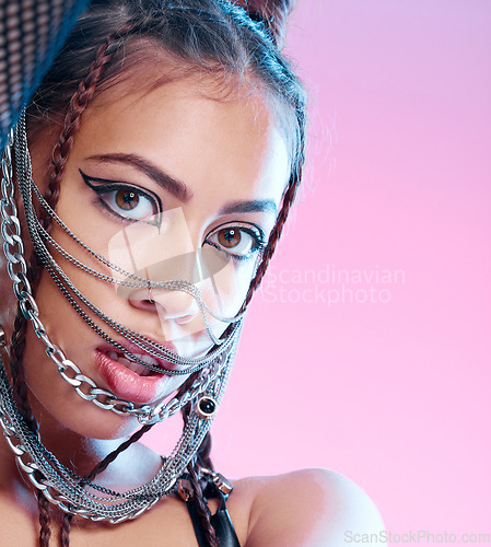 Image of Chains, style and portrait of goth woman with unique fashion isolated against a studio pink background. Face, accessories and edgy female model metal jewelry on her head and cool makeup