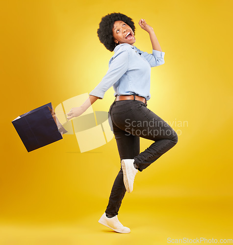 Image of Bag, happy and black woman shopping, excited and celebrating sale in studio on yellow background. Discount, shopper and girl customer cheerful after boutique, retail or store deal posing isolated