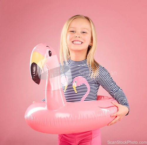 Image of Safety, happy and portrait of girl and pool float for swimming, summer break and relax. Youth, funny and inflatable with child and flamingo ring for pool, smile and beach holiday on pink background