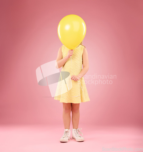 Image of Balloon cover face, girl and child in studio isolated on a pink background mockup. Children, birthday party and celebration event with young shy kid hiding with yellow air ballons and inflatable.