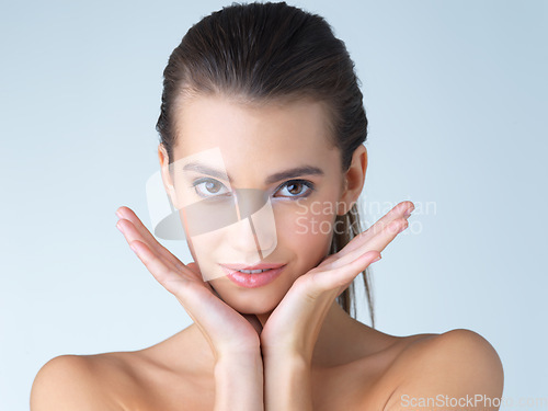 Image of Woman, makeup and hands on face in studio for skincare, wellness or cosmetics on blue background. Portrait, beauty and girl model with dermatology, satisfaction or luxury skin routine while isolated