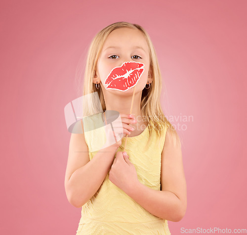 Image of Portrait, children and lips with a girl on a pink background in studio holding a mouth prop. Kids, emoji and kiss with an adorable little female child holding a cardboard shape for valentines day