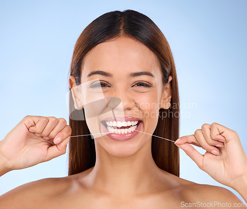 Image of Dental floss, happy portrait and woman smile with teeth hygiene, healthcare and wellness treatment. Isolated, blue background and studio with a female feeling beauty from a clean mouth with self care