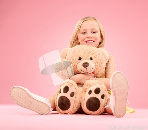 Image of Teddy bear love, girl and portrait with a soft toy with happiness and care for toys in a studio. Isolated, pink background and a young female child feeling happy, joy and cheerful with stuffed friend