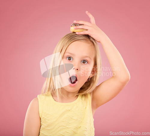 Image of Child, donut and wow face portrait in studio with hand on head on a pink background. Girl kid model with sweet snack, surprise and shocked or comic expression isolated on creative color and space