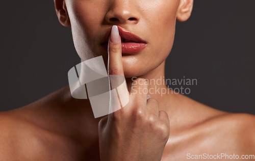 Image of Finger, lips and beauty with a model woman in studio on a gray background for skincare or cosmetics. Hand, makeup and mouth with a female touching her lip to promote a lipstick or cosmetic product