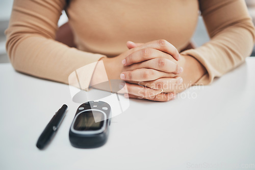 Image of Hands, diabetes and glucose machine on table for woman with medical problem, self care or wellness. Monitor, glucometer or blood test of sugar level, healthcare or insulin for patient at desk in home