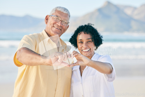 Image of Hands, heart and a senior couple on the beach together during summer for love, romance or weekend getaway. Portrait, travel or emoji with a mature man and woman bonding outdoor on sand by the coast