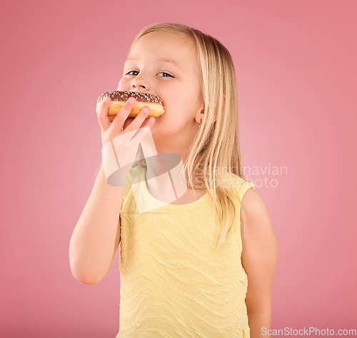 Image of Portrait, girl kid and donuts on pink background, studio and color backdrop for dessert, sweet round treat and sugar. Happy young child eating doughnut, baked snack and delicious pastry of junk food