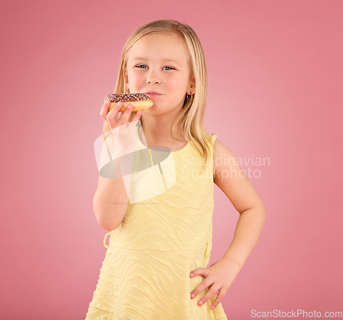 Image of Portrait, girl child and donuts on pink background, studio and color backdrop for dessert, sweet treat and sugar. Happy young kid eating doughnut, baked snack and delicious round pastry of junk food