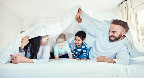 Image of Family, blanket and fun by children and parents in bed, happy and smile while playing and bonding in their home. Bedroom, fort and kids with mother and father, waking up and enjoying weekend indoors