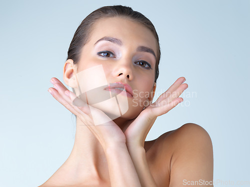 Image of Makeup, woman and hands on face in studio for skincare, wellness or cosmetic on blue background. Portrait, beauty and girl model with dermatology, satisfaction or luxury skin routine while isolated