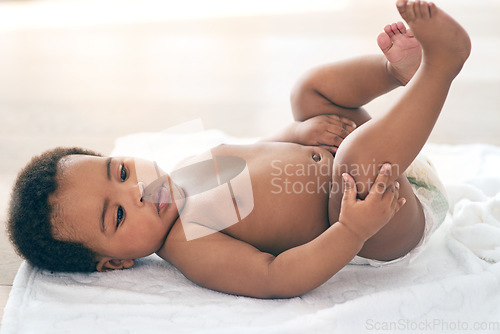 Image of Calm, cute and baby on a bed with a diaper, relax and curious while looking at feet at home. Black child, infant and adorable boy on a changing table, comfortable and relaxing alone in a nursery