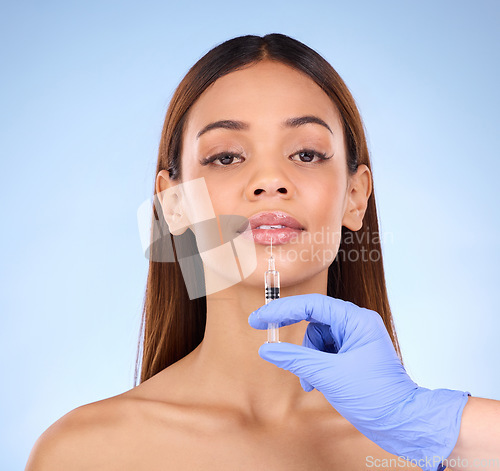 Image of Portrait, lips and injection of woman on studio, blue background and facial beauty. Young female model, lip filler and needle for plastic surgery, skincare transformation and aesthetic face change