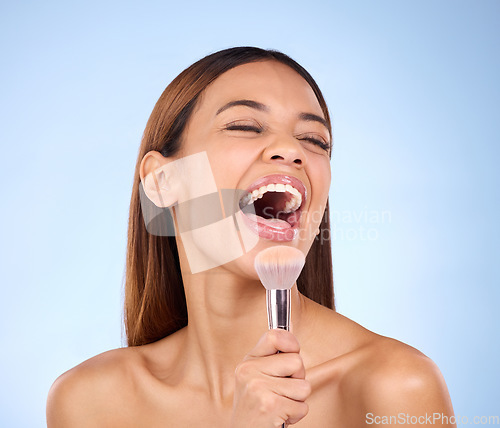 Image of Skincare, beauty and woman with brush, makeup and happiness against blue studio background. Female, lady and cosmetics tool with laugh, foundation and natural skin glow with joy, cheerful and facial