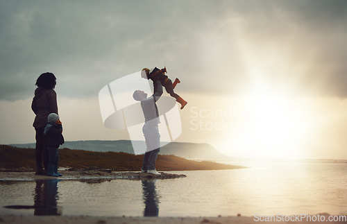 Image of Sunset, view and a playing family on the beach together on a beautiful summer evening outdoor. Earth, water or nature with a mother, father and children bonding by the ocean or sea at the coast