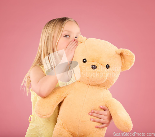 Image of Teddy, secret and young girl talking and whispering to a toy bear in a studio. Playing, child and bonding with love and care for toys with isolated pink background in a happy discussion together