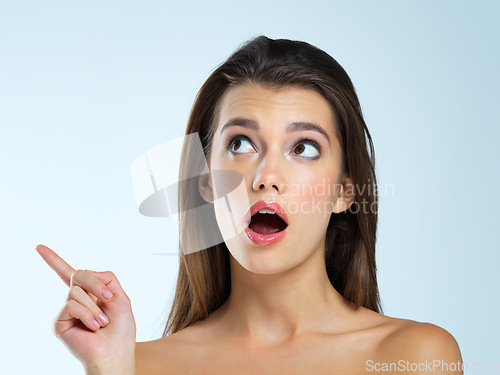 Image of Wow, pointing and beauty woman isolated on blue background for sale, discount or makeup promotion deal. Surprise face of cosmetics model or young person in studio showing mockup or product placement