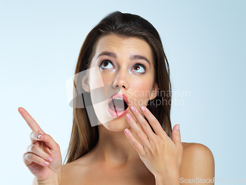 Image of Wow, shocked and pointing woman isolated on blue background beauty sale, discount or makeup promotion. Surprise face of cosmetics model or gossip person in studio showing mockup or product placement