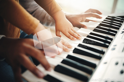 Image of Hands, parent and child playing piano as development of skills together and bonding while making music in a home. Closeup, musical and kid learning a song on an instrument and father teaching