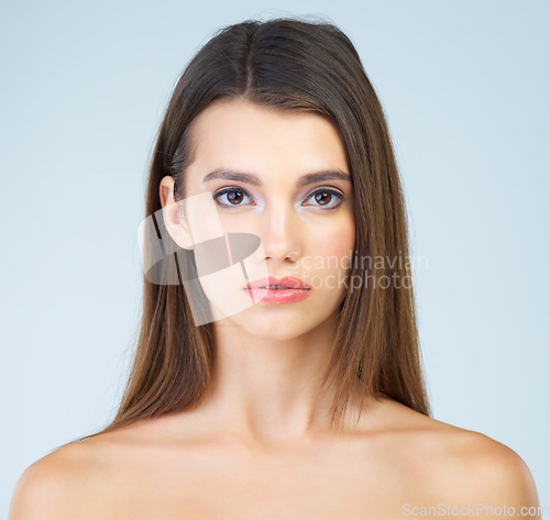 Image of Portrait, beauty and woman with makeup, skincare and self care and glow or soft skin isolated in studio blue background. Face, headshot and serious clean female model for cosmetic health