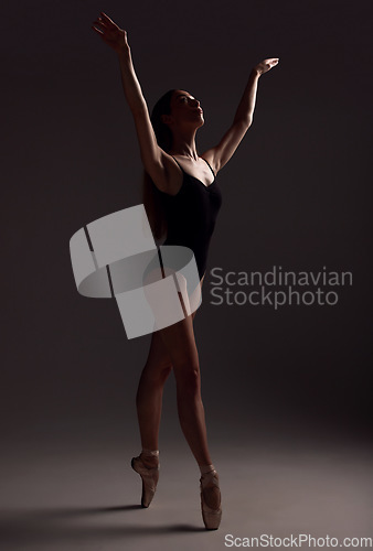 Image of Ballet, woman and dancer with routine, fitness and training for performance on a dark studio background. Female performer, lady and ballerina with wellness, focus and commitment for art or creativity