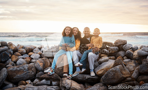 Image of Black family, parents and children in beach portrait with excited face, sitting and rocks with happiness. Black woman, man and kids by ocean with love hug, care and bonding on holiday by sunset sky