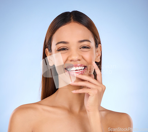 Image of Portrait, skincare and woman with laugh, cosmetics and happiness against blue studio background. Face, Latino female and lady with smile, dermatology and morning routine for confidence and soft skin