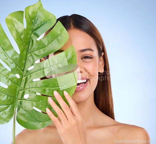 Image of Happy woman, portrait and leaf in natural beauty and organic skincare cosmetics for self love or care on blue studio background. Female with smile holding eco green plant for sustainable wellness