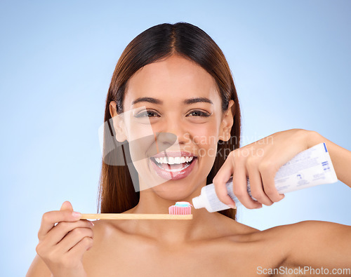 Image of Portrait, toothbrush and dental with a model woman in studio on a blue background for oral hygiene. Mouth, cleaning and smile with an attractive young female brushing her teeth for whitening