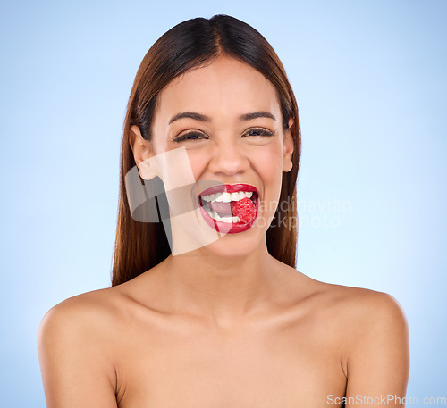 Image of Beauty, health and raspberry with woman in studio for nutrition, diet and detox. Organic food, natural cosmetics and self care with girl model eating fruit on blue background for wellness and glow