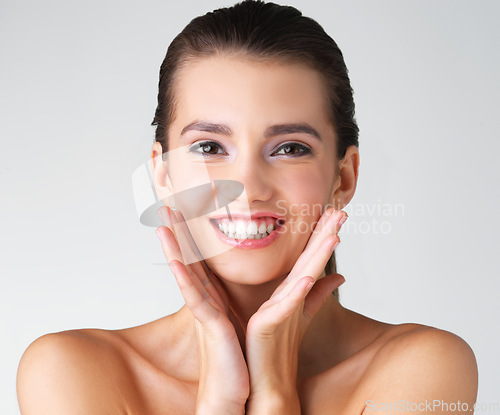 Image of Happy, woman and hands on face in studio for makeup, wellness or cosmetic on grey background. Portrait, smile and girl beauty model with dermatology, satisfaction or luxury routine while isolated