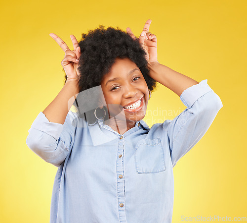 Image of Goofy, happy and portrait of a black woman in a studio with a silly, funny and comic gesture. Happiness, smile and African female model with peace sign for bunny ears on her head by yellow background