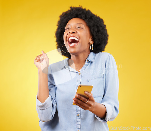 Image of Happy, excited and phone with black woman in studio for text message, notification and social media news. Deal, winner and celebration with girl on yellow background for offer, giveaway and surprise