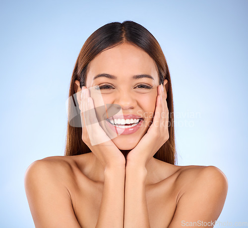 Image of Skincare, hands on face and portrait of woman laughing in studio for skin care promo on blue background. Makeup, facial cosmetics and smile, hispanic beauty model in Mexico for dermatology promotion.