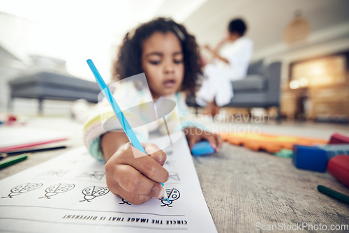 Image of Child hand, coloring homework and pencil art of a girl lying on a living room carpet at home. House, color learning and creative development activity of young kid in kindergarten with a school book