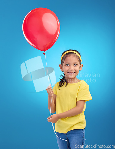 Image of Happy girl, studio and red balloon of a an excited kid with a smile ready for a birthday party. Celebration, happiness and young child holding balloons in the air with isolated blue background