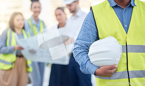 Image of Helmet, construction and an architect standing on a building site with his team planning in the background. Leadership, architecture and renovation with an engineer holding a hard hat for maintenance