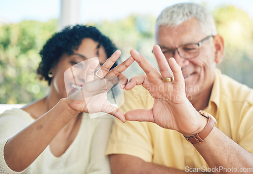 Image of Senior couple, hands and heart emoji for love, relationship or trust and care in marriage at home. Happy elderly man and woman putting hand together in hearty shape sign, symbol or gesture in romance