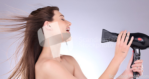 Image of Beauty, straight hair and a woman blowing her hairstyle in studio on a gray background for grooming or style. Salon, cosmetics or salon with an attractive young female indoor to blowdry while styling