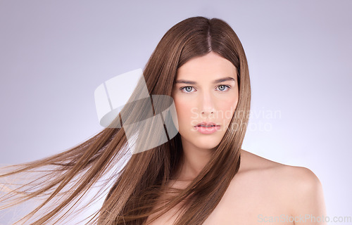 Image of Portrait, hair and windy with a model woman in studio on a gray background for haircare or keratin treatment. Shampoo, salon and beauty with an attractive young female posing in a breeze on a wall