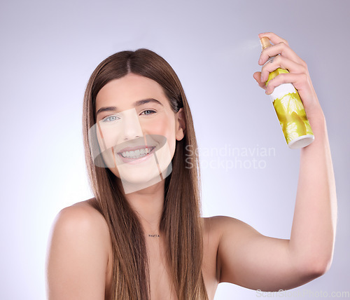 Image of Beauty face, hair care and woman with spray in studio isolated on a gray background. Cosmetics, portrait smile and happy female model with hairspray product for salon treatment, growth and hairstyle.
