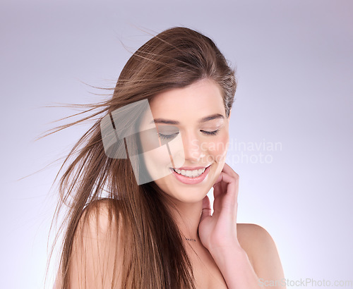 Image of Beauty, hair and wind with a model woman in studio on a gray background for haircare or keratin treatment. Shampoo, salon and natural with an attractive young female posing in a breeze on a wall