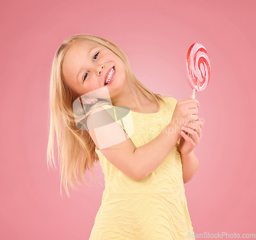 Image of Candy, happy and lollipop with portrait of girl in studio for sugar, party and carnival food isolated on pink background. Cute, positive and youth with child and eating snack for playful and treats