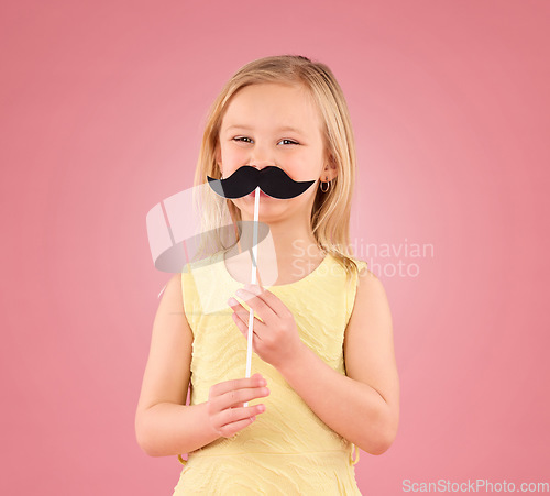 Image of Girl, child and portrait in studio with moustache prop on a pink background with a smile and stick. Female kid model with happiness, creativity and comic icon in hand isolated on a color and space